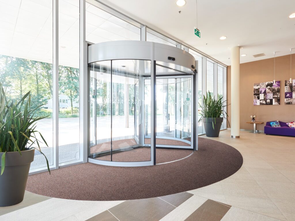 HOSPITALITY A commercial entrance featuring a large Rinos mat, showcasing the practical application of ECONYL® regenerated nylon in high-traffic areas.
